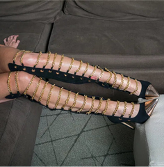 Person wearing gold studded high-heeled shoes on a couch.
