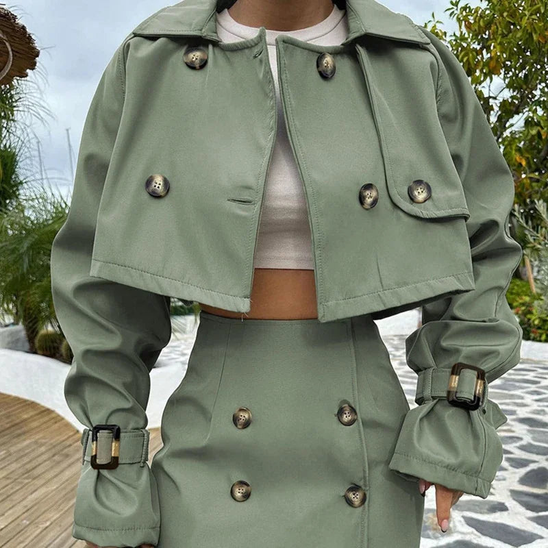 Person wearing a green trench coat with button details outdoors.