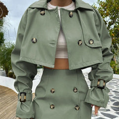 Person wearing a green trench coat with button details outdoors.