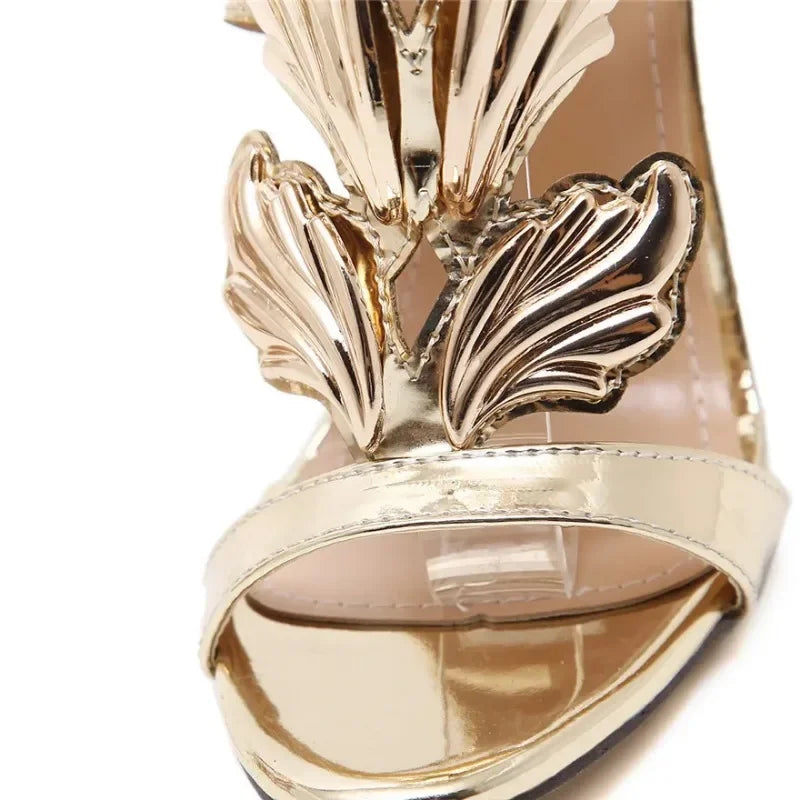 Close-up of gold metal wing embellishment on stiletto heel