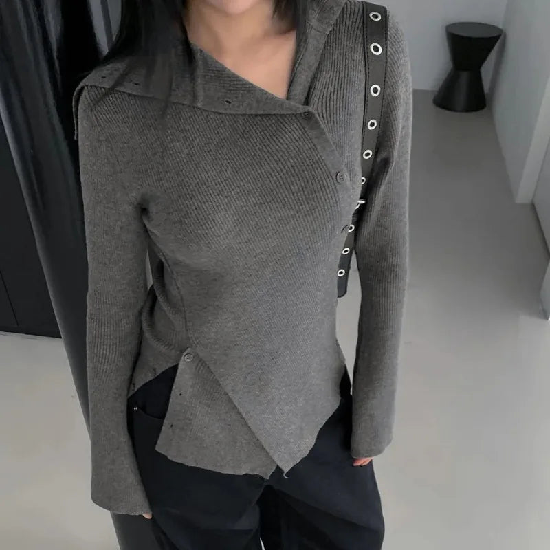 Person wearing a gray textured cardigan with unique button design on a neutral background