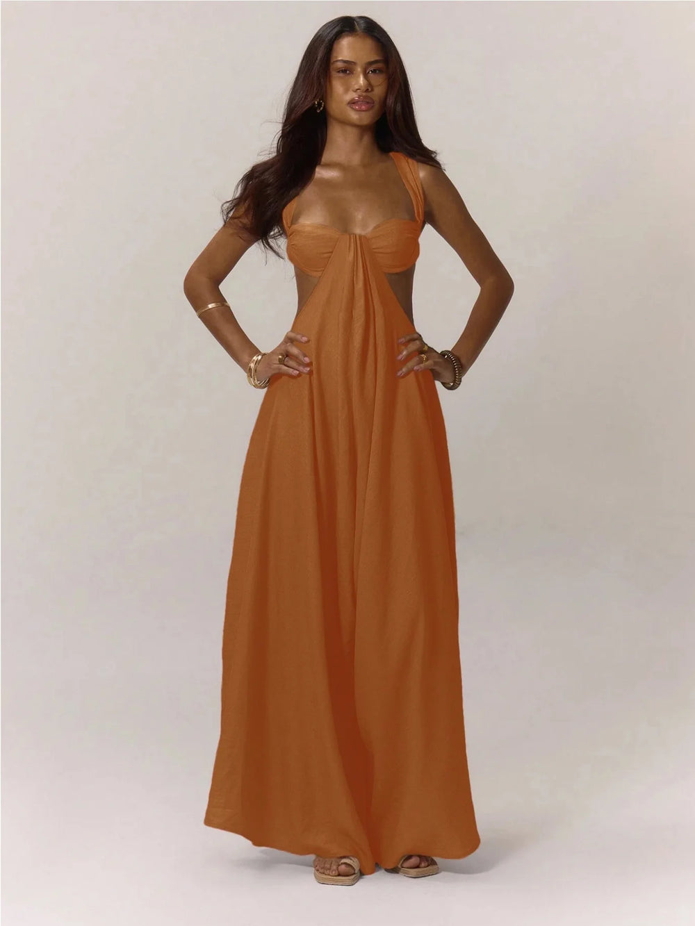 Woman wearing a long orange jumpsuit against a white background