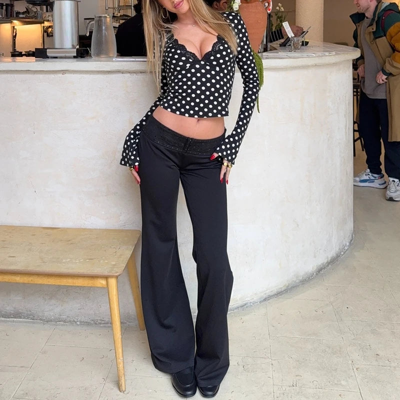 Woman wearing a black and white polka dot top and black pants in an indoor setting.