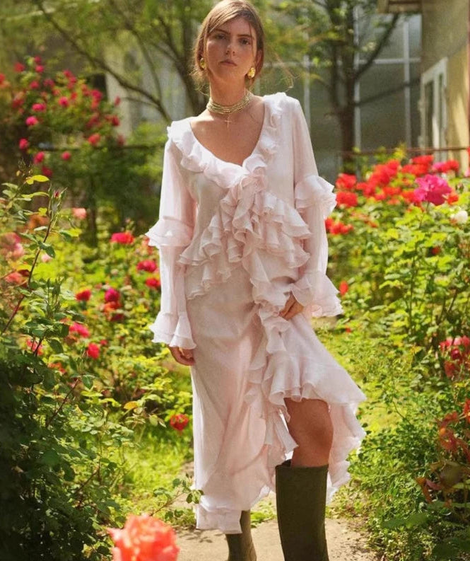 Woman in a pink ruffled dress standing in a garden with flowers