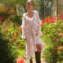 Woman in a pink ruffled dress standing in a garden with flowers