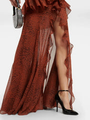 Long rust-colored dress with ruffles and a high slit, paired with black high heels on a white background.