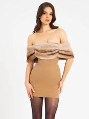 Woman wearing a tan dress with a fur-like overlayer on a white background