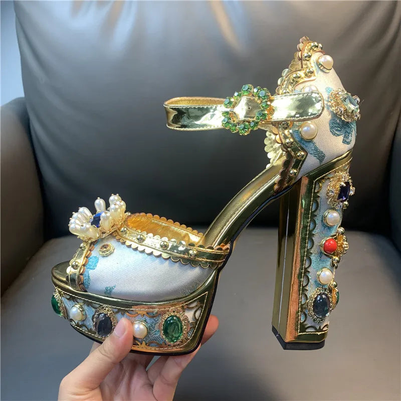 Decorative high-heeled shoe with gold accents and gemstones held by a hand.