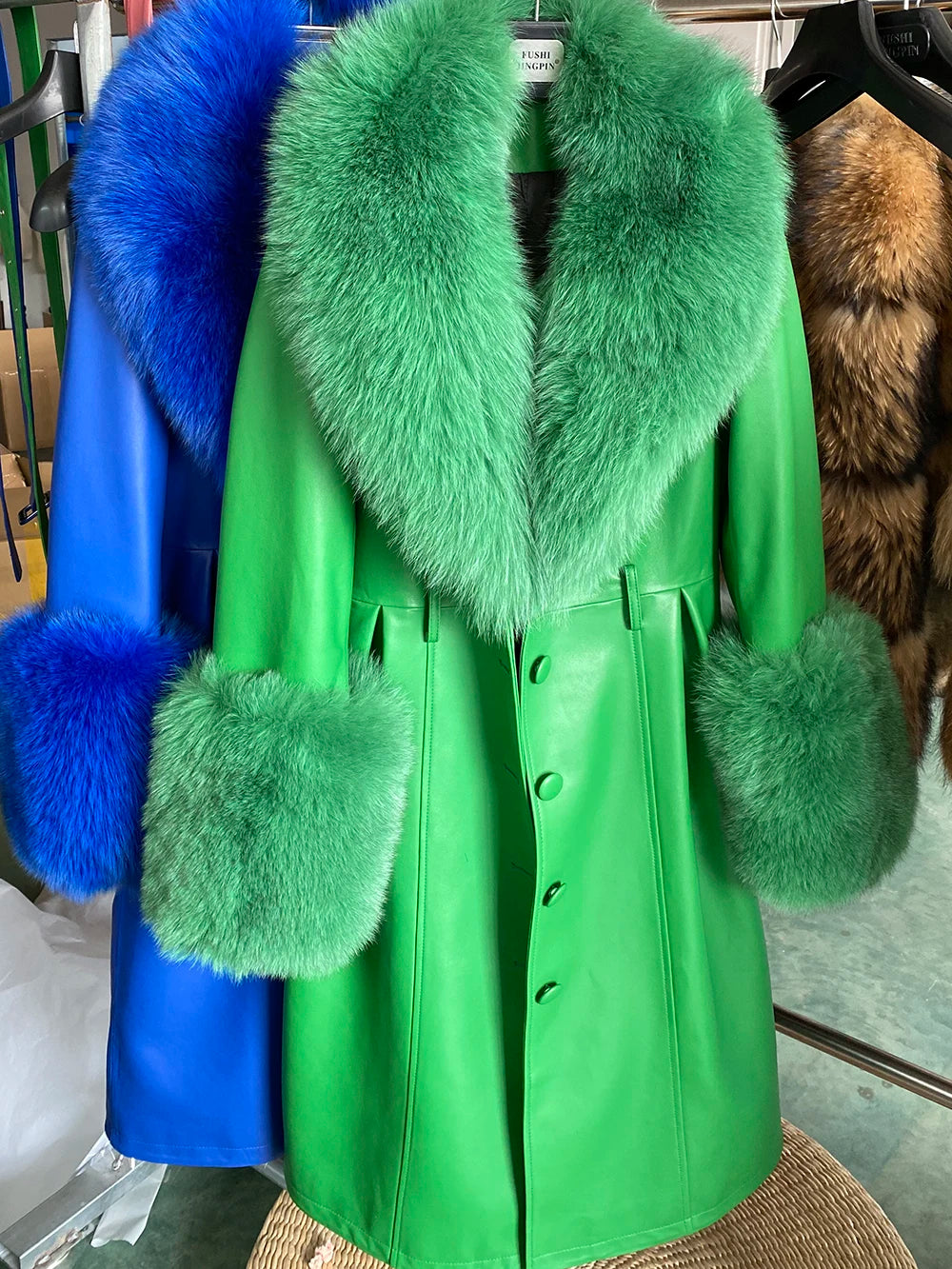 Green coat with fur trim on a rack