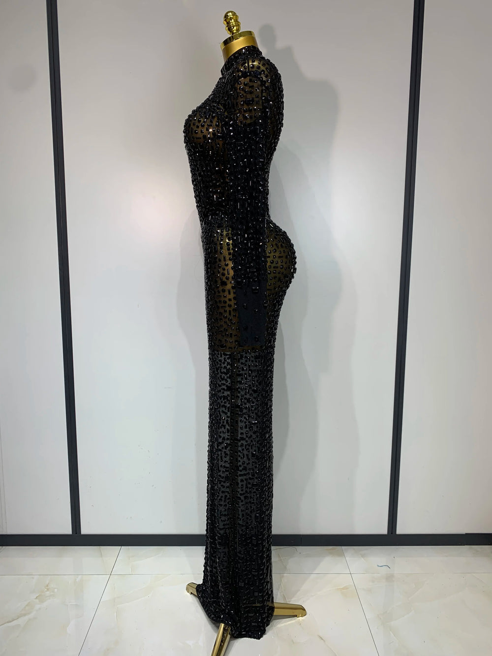 Black beaded evening gown on a mannequin against a white background