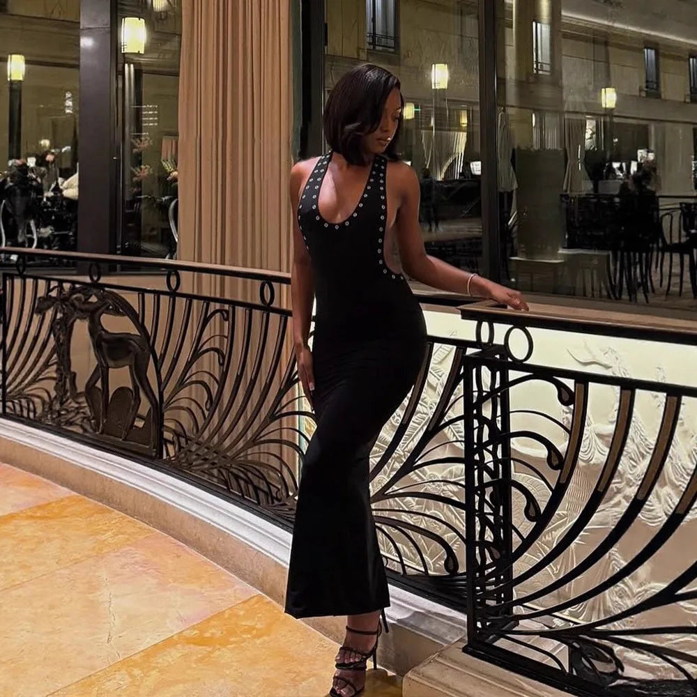 Woman leaning on a railing in a halter neck studded side cutout maxi dress indoors