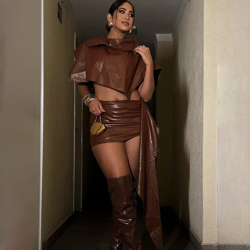 Woman in a brown leather outfit standing in a hallway.