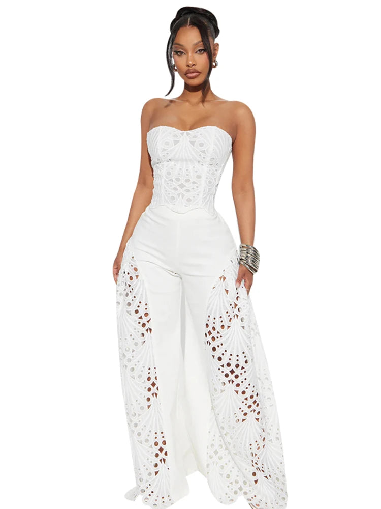 Woman wearing a white strapless jumpsuit with lace details on a white background