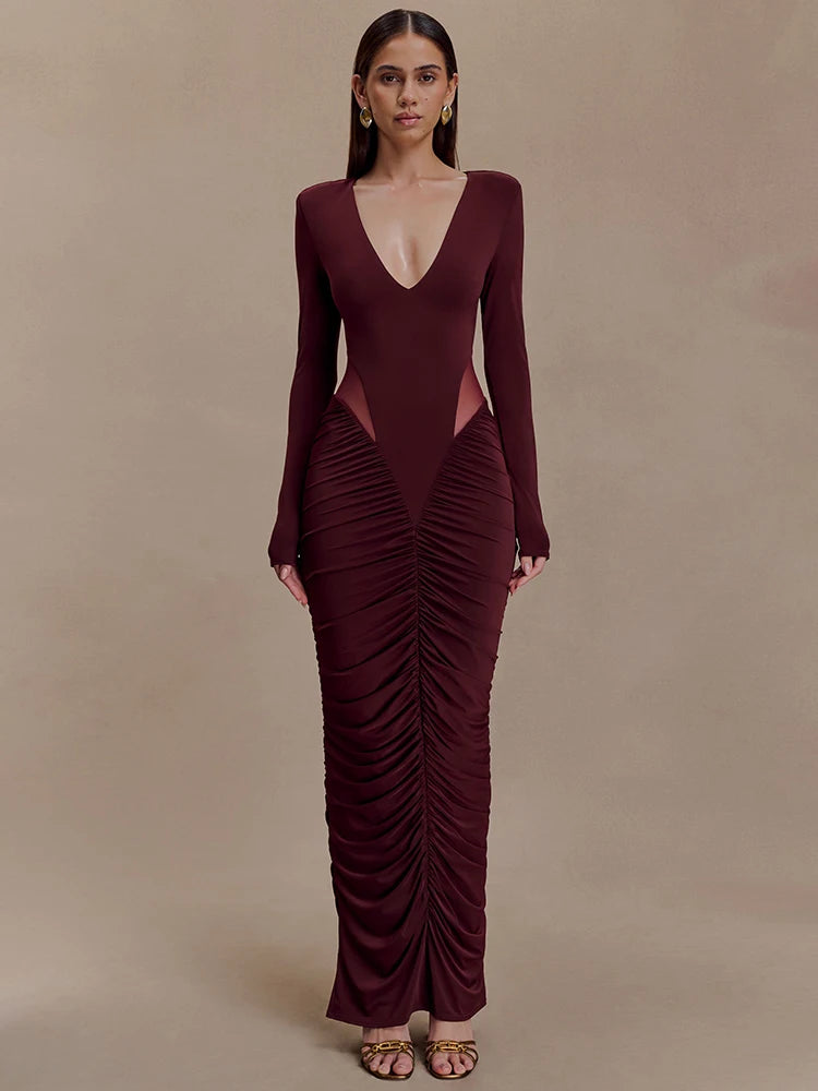 Woman wearing a burgundy evening gown with a deep neckline and ruched design on a beige background