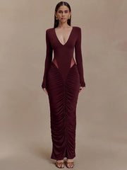 Woman wearing a burgundy evening gown with a deep neckline and ruched design on a beige background
