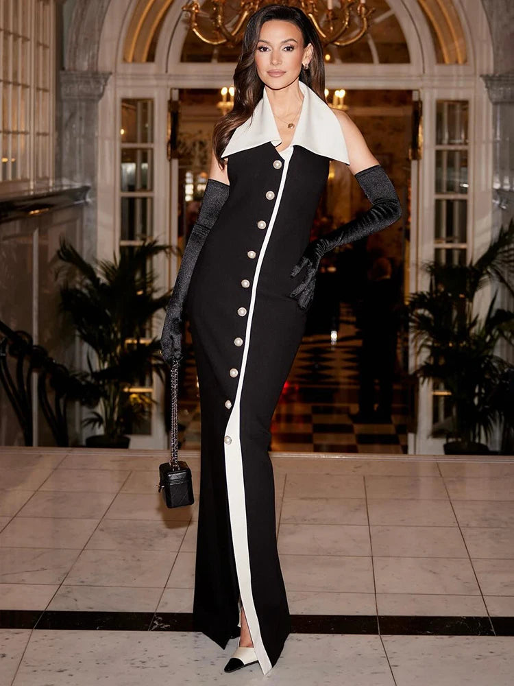 Woman in a black and white dress with long gloves standing in an elegant interior setting.