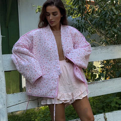 Floral quilted kimono jacket draped over a model leaning on a fence