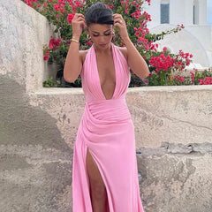 Woman in a pink dress standing outdoors with flowers and a building in the background