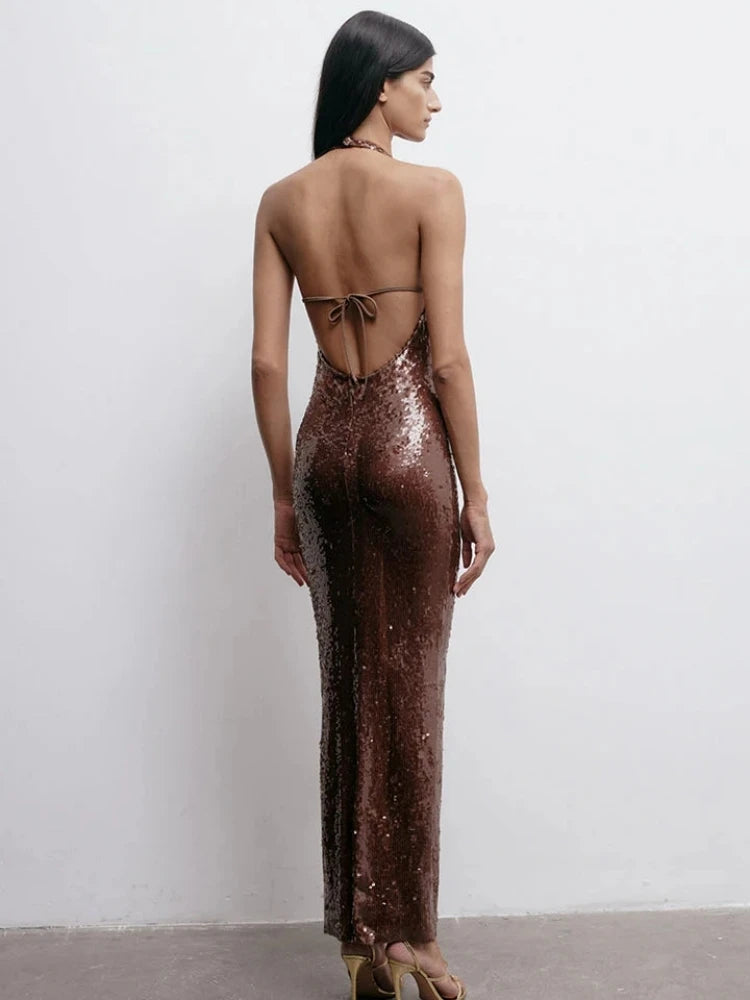 Woman wearing a long, backless brown sequin dress against a white background