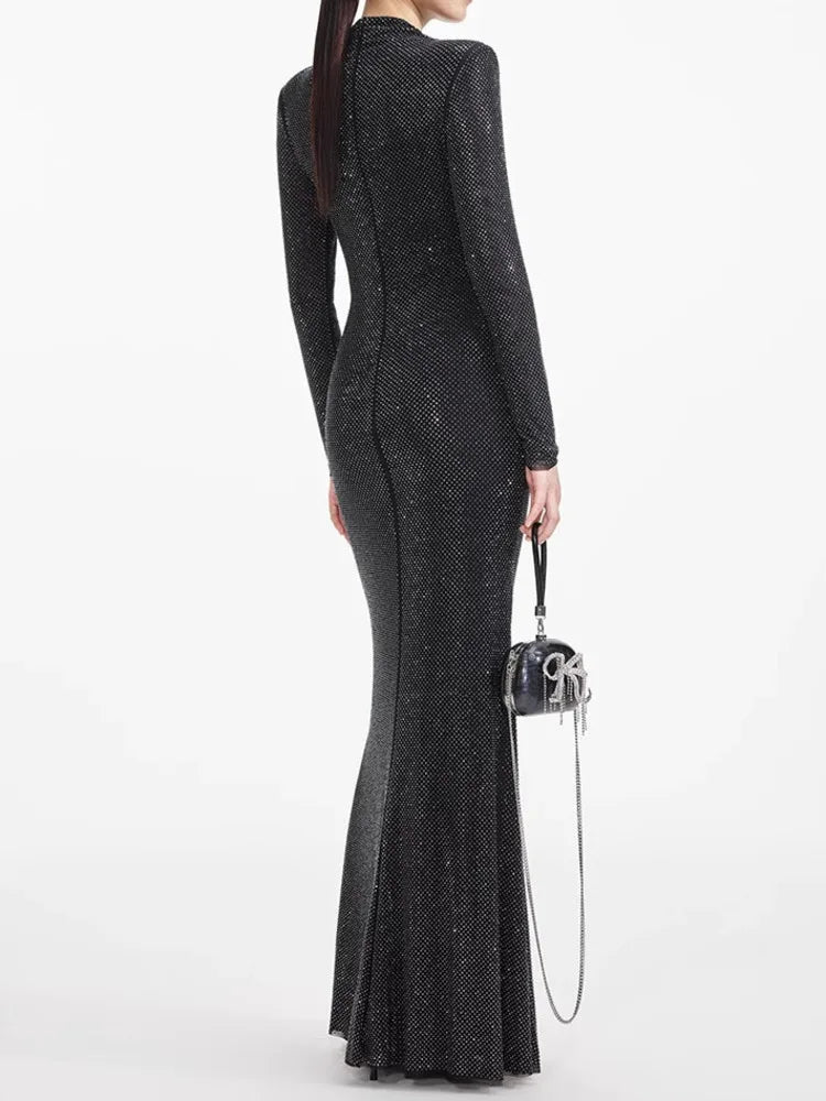 Woman wearing a black sequin dress holding a matching handbag on a white background