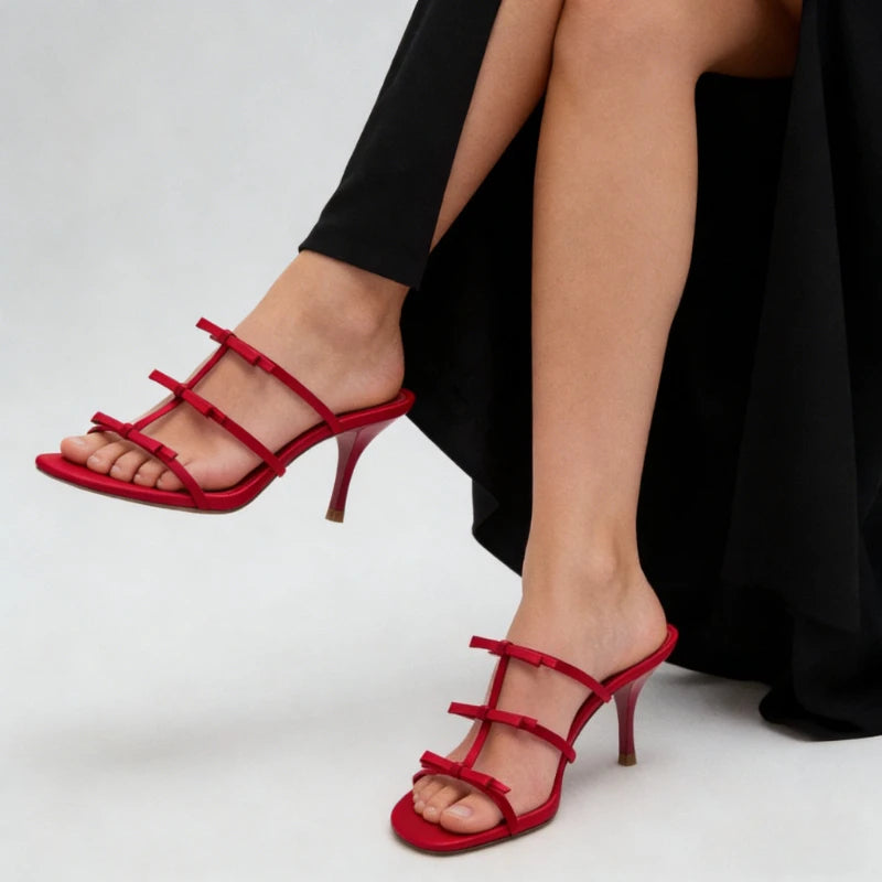 Model wearing red stiletto heels with bow straps.