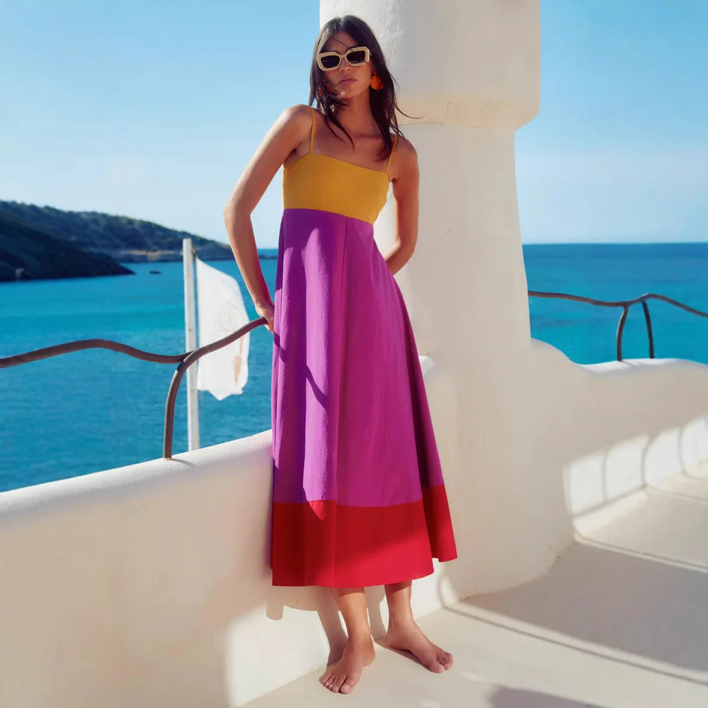 Woman wearing a contrast color strappy midi dress with defined waist and tiered hem