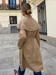 A stylish woman wearing a double-breasted trench coat with a shawl collar and belt, showcasing its elegant design.