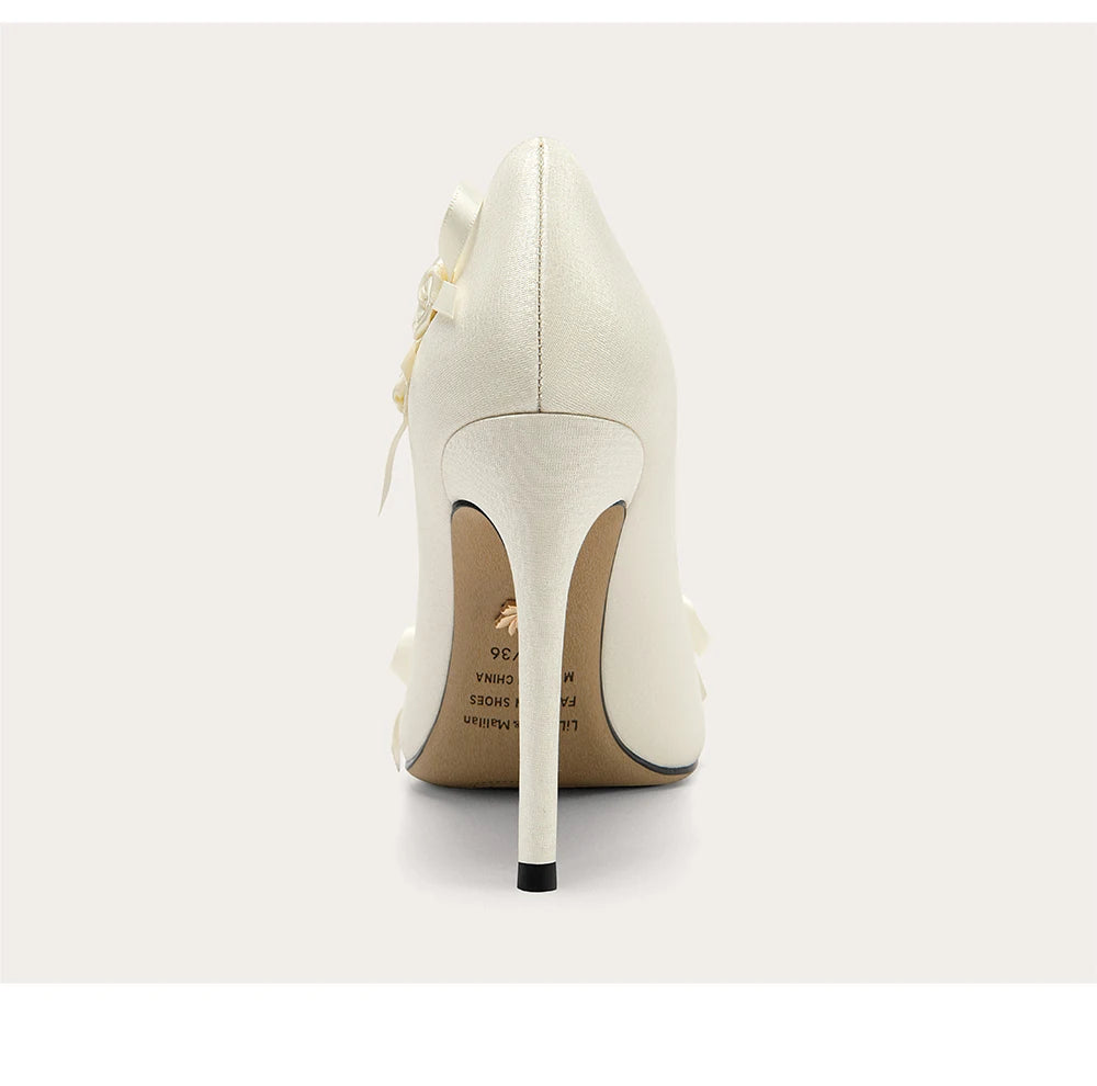 White high-heeled shoe with a decorative bow on a light gray background