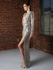 Woman in a silver sequin dress standing against a brick wall.