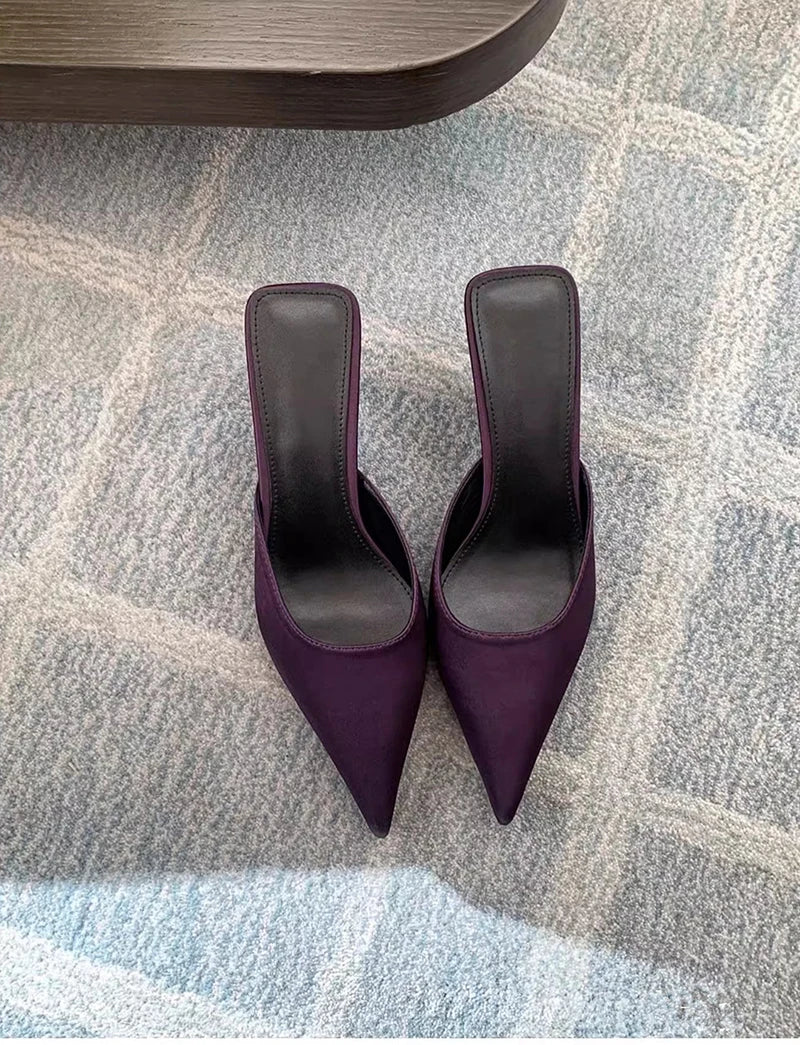 Pair of purple high-heeled shoes on a patterned carpet