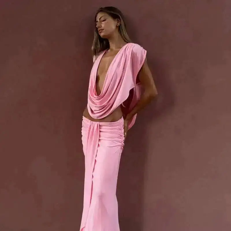 Pink draped plunge neckline maxi dress against a wall.