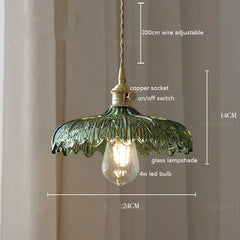 Close-up of a vintage green glass pendant lamp, showcasing the textured glass and warm glow of the LED bulb. Dimension 1