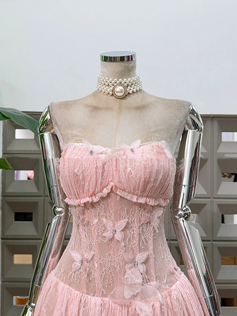 Mannequin wearing a pink lace dress with a pearl necklace against a neutral background
