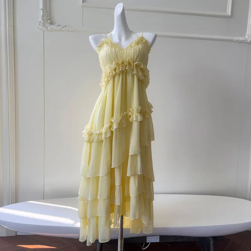 Yellow ruffled chiffon maxi dress on a white mannequin, front view on a table.