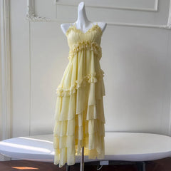 Yellow ruffled chiffon maxi dress on a white mannequin, front view on a table.