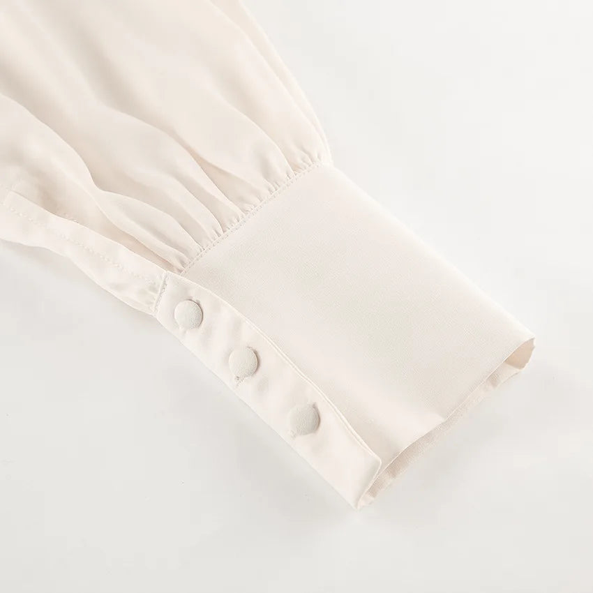 Close-up of a cream-colored garment with button details on a light gray background