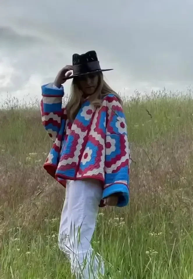 Model wearing a geometric quilted kimono jacket in a field.