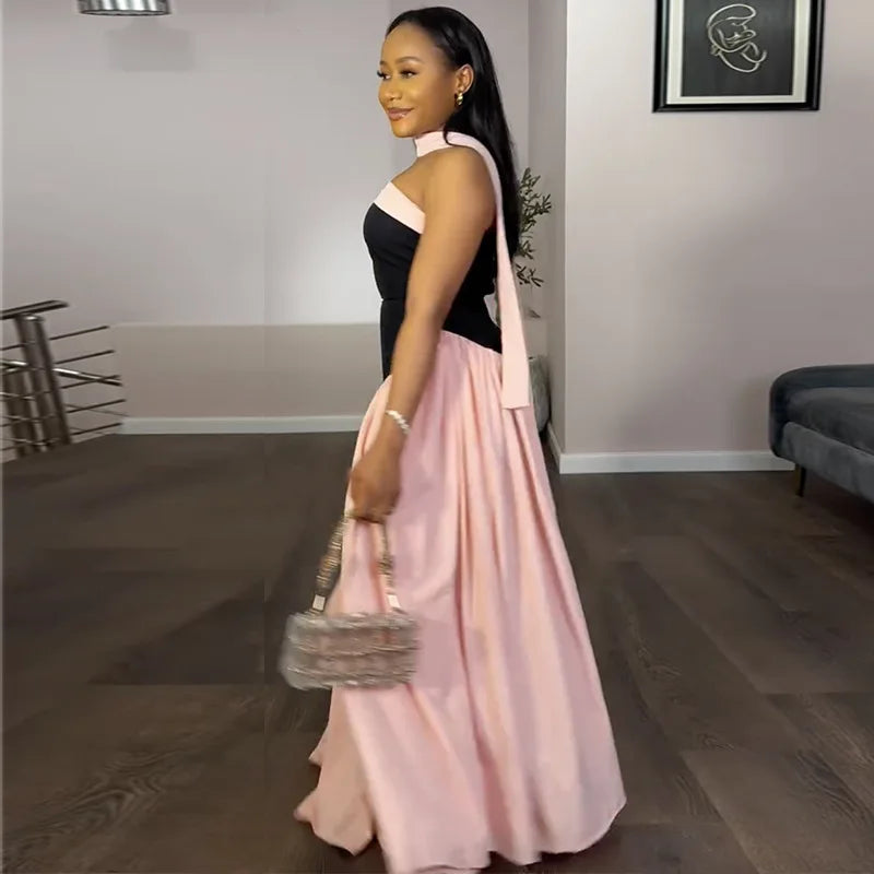 Woman in a black and pink dress holding a handbag in a room with a couch and plant.