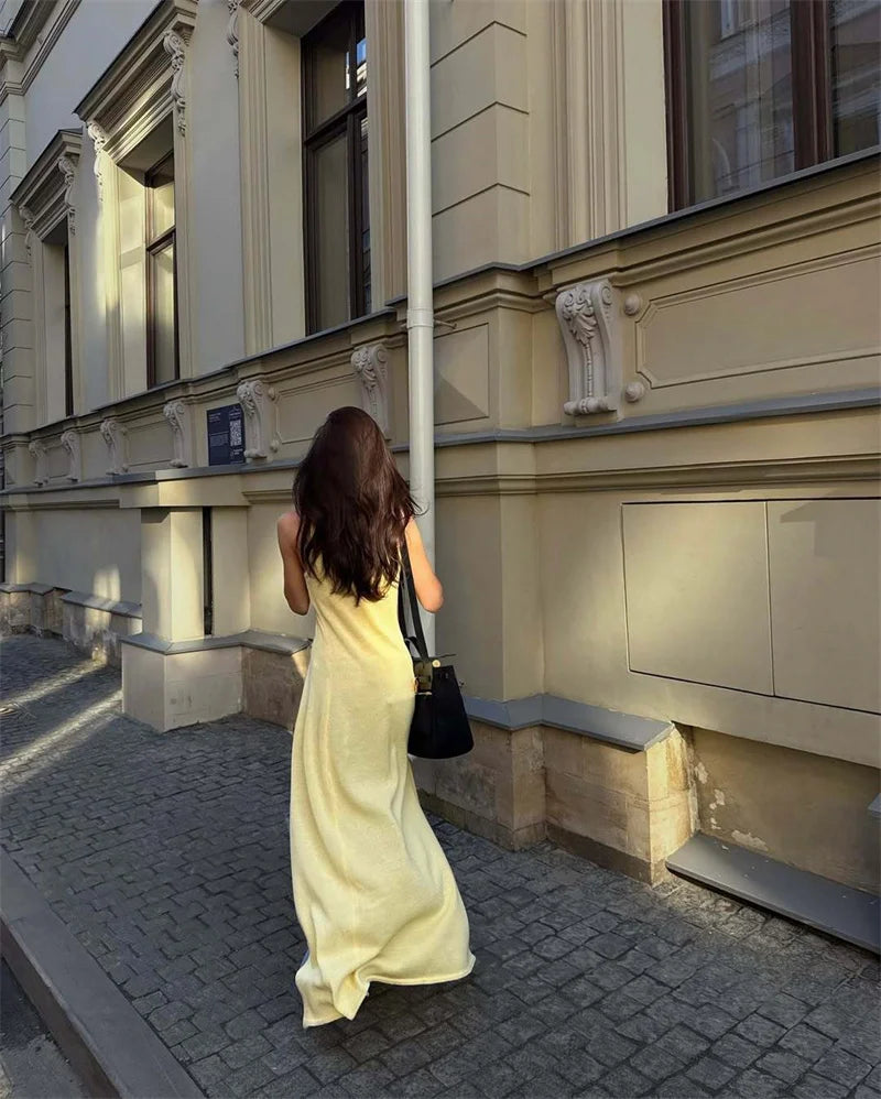 Woman in a yellow dress walking down a street next to a building.
