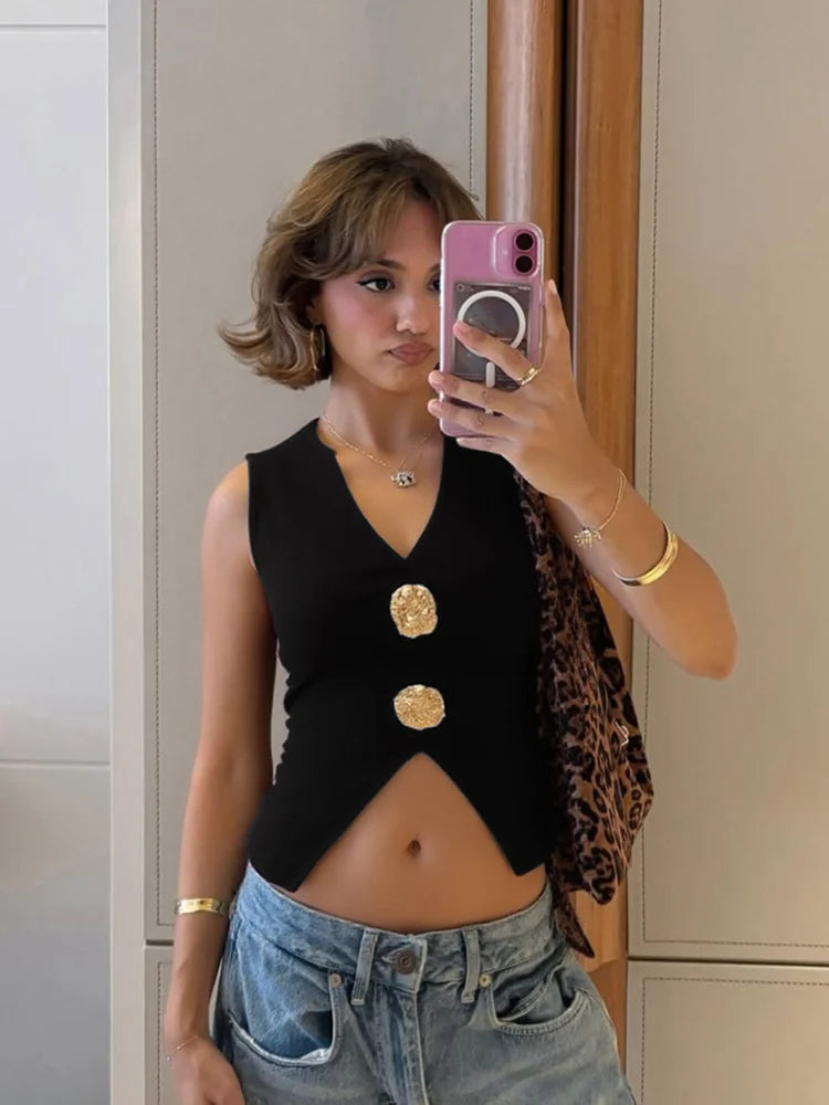 Person taking a mirror selfie wearing a black sleeveless top with gold buttons, leopard print cardigan, and denim shorts.