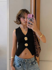 Person taking a mirror selfie wearing a black sleeveless top with gold buttons, leopard print cardigan, and denim shorts.
