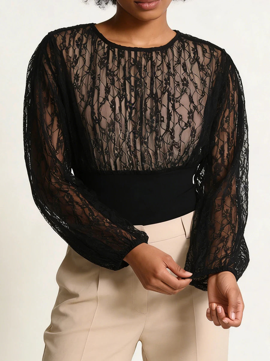 Black lace top worn by a person on a plain background
