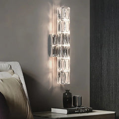 An elegant crystal wall light with a long arm and a decorative shade, adding a touch of luxury to a bedroom.