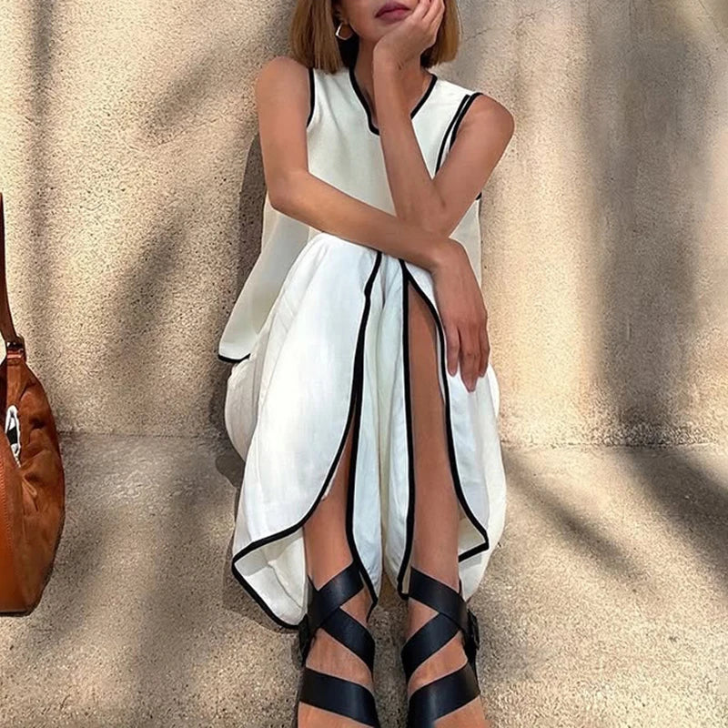 Woman wearing a white dress with black trim against a beige curtain background