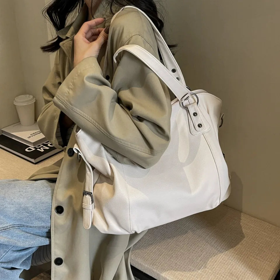 White tote bag held by a person wearing a trench coat
