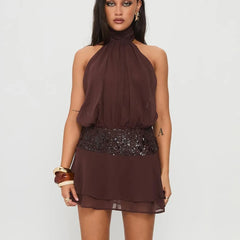 Woman wearing a brown halter neck dress with sequin details on a white background