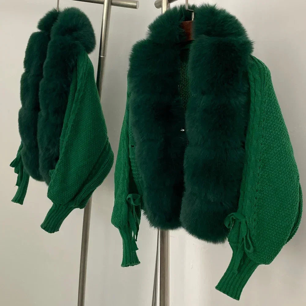 Green knitted sweater with fur collar on a rack against a white background
