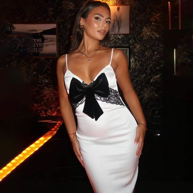 Woman in a white dress with a black bow detail in a dimly lit setting