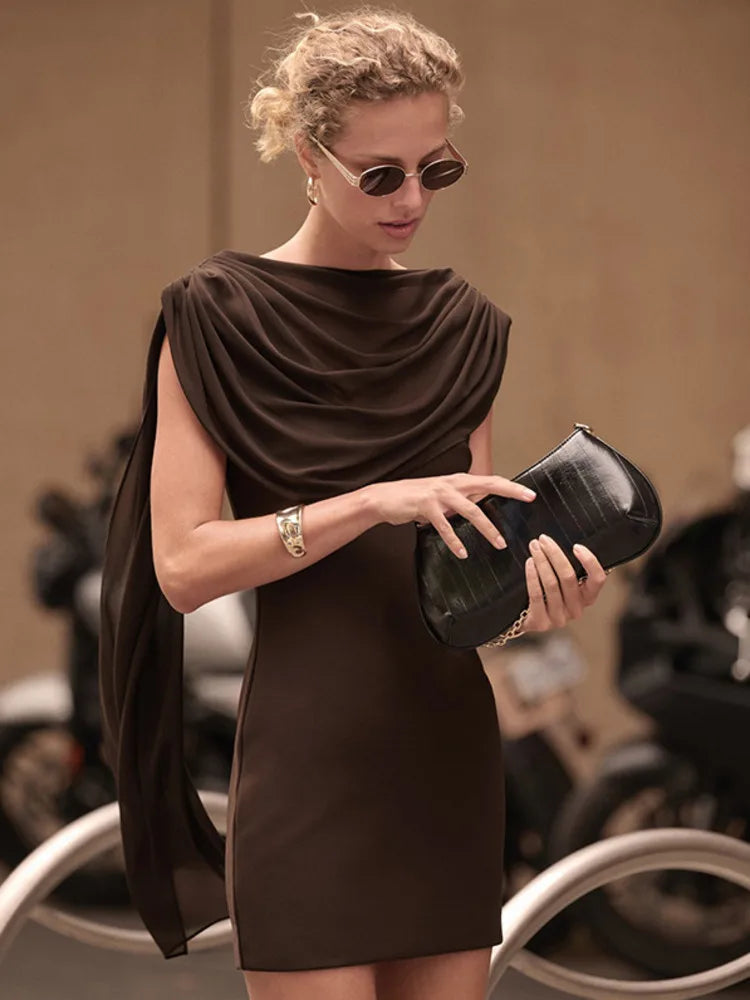 Woman in a brown dress holding a black clutch with a blurred background