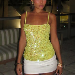 Woman wearing a sparkly yellow top and white skirt in an indoor setting.